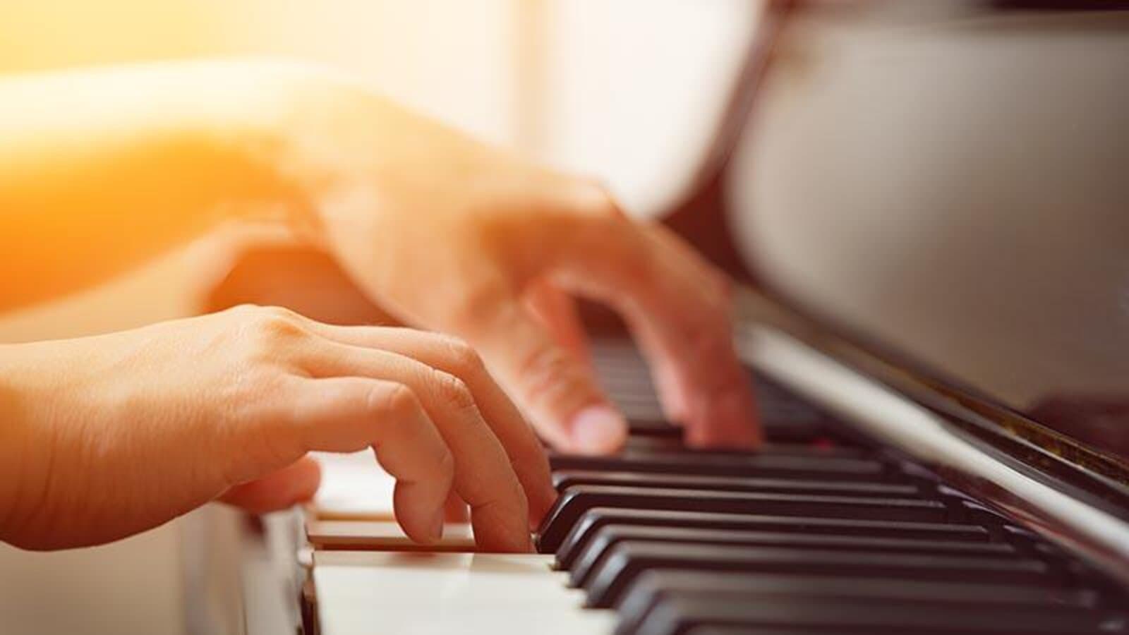 Close-up of hands playing piano keys in warm golden light
