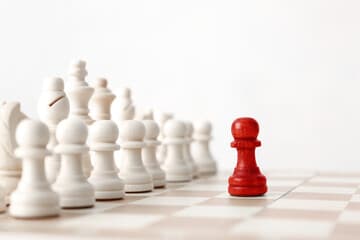 Two chess pieces facing off under red and blue lighting.