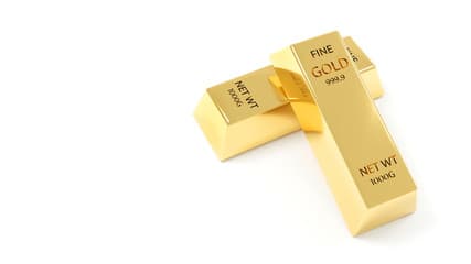 Stacked gold bars inside a vault under soft directional lighting.