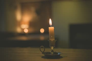 A single lit candle on a table in a dark room.