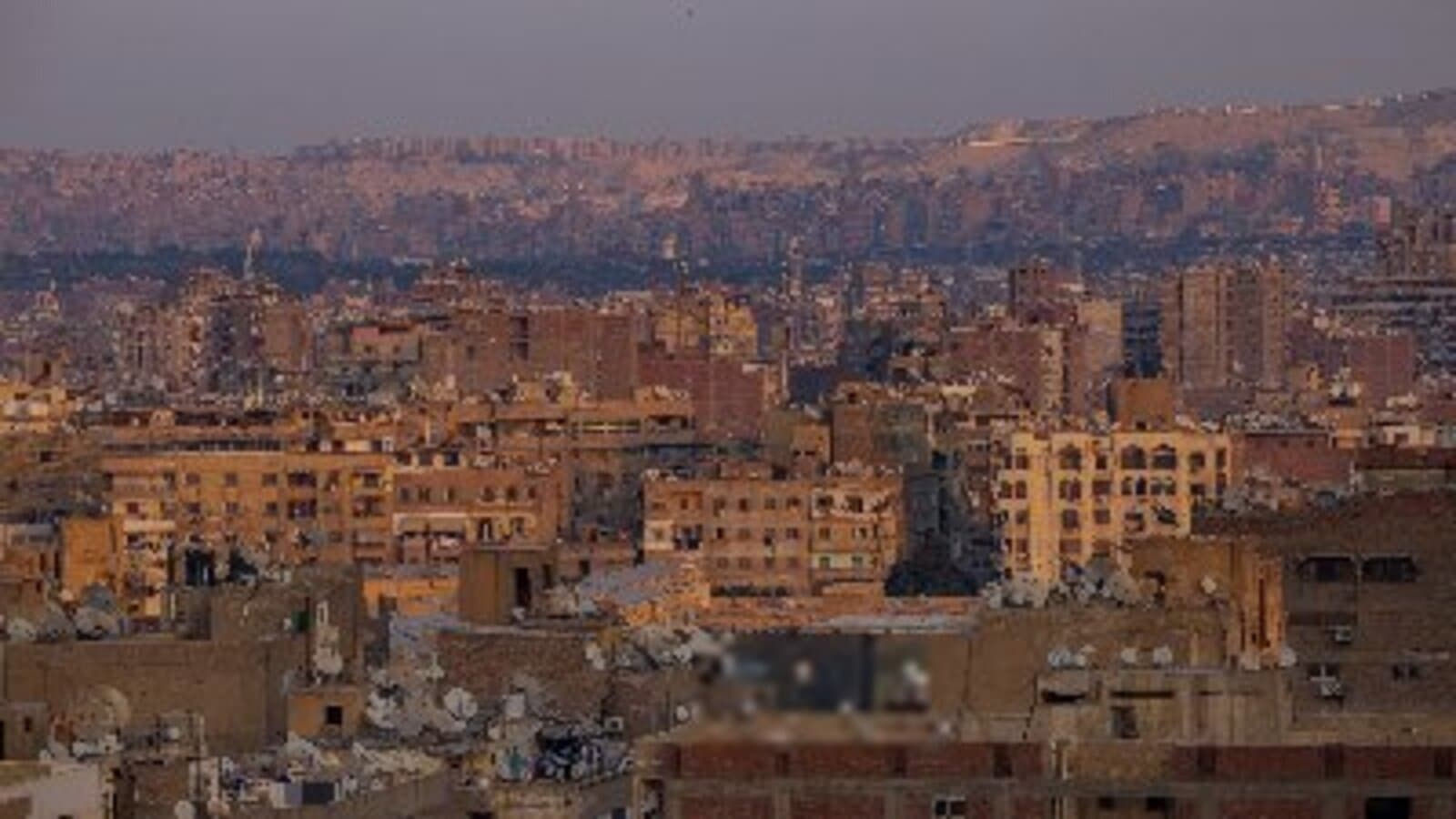 Aerial view of dense residential urban terrain in the Middle East at dusk with hazy hills in the background